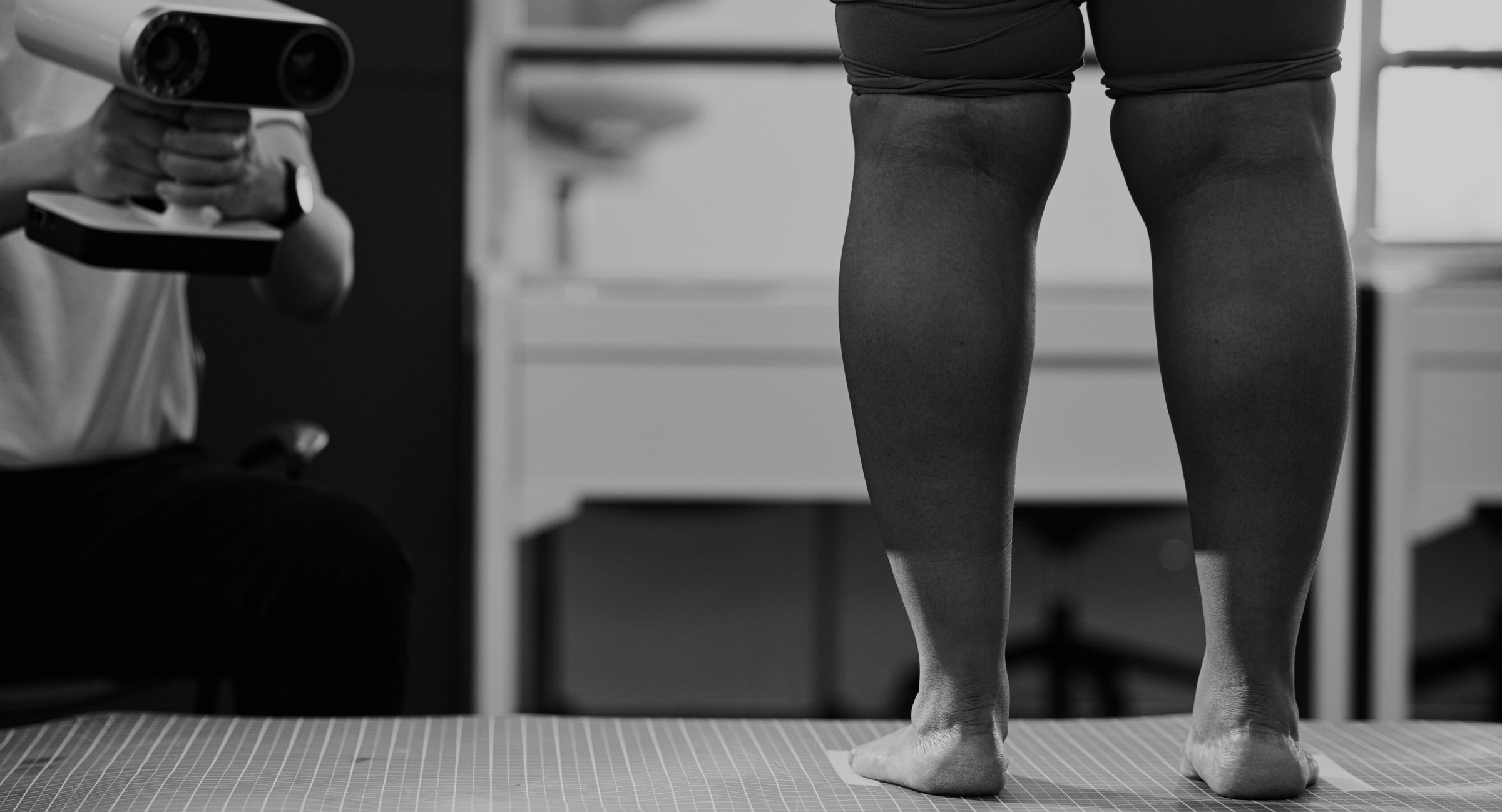 model standing on a table, having their feet and calves measured